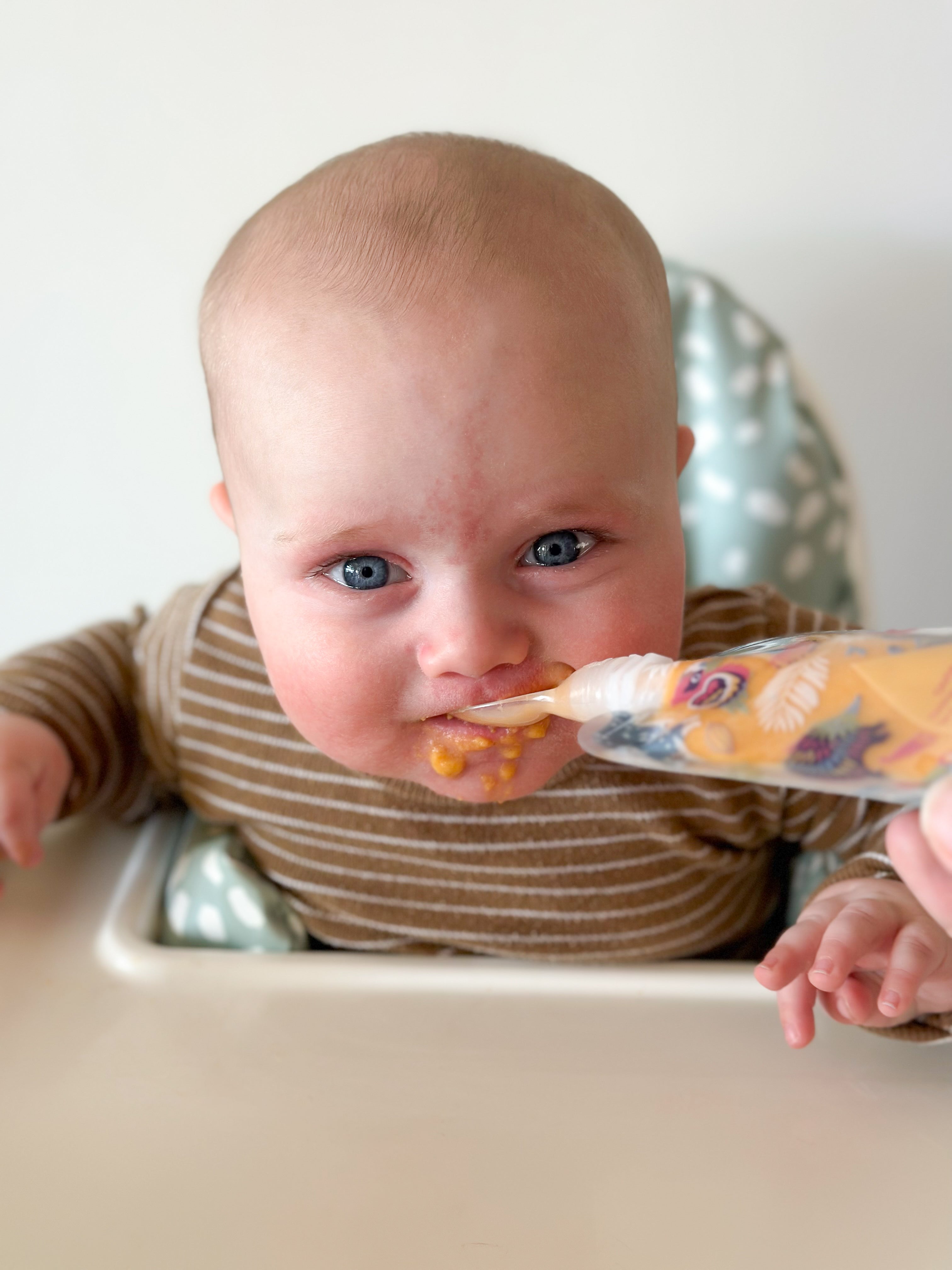 baby eating homemade puree from reusable food pouch