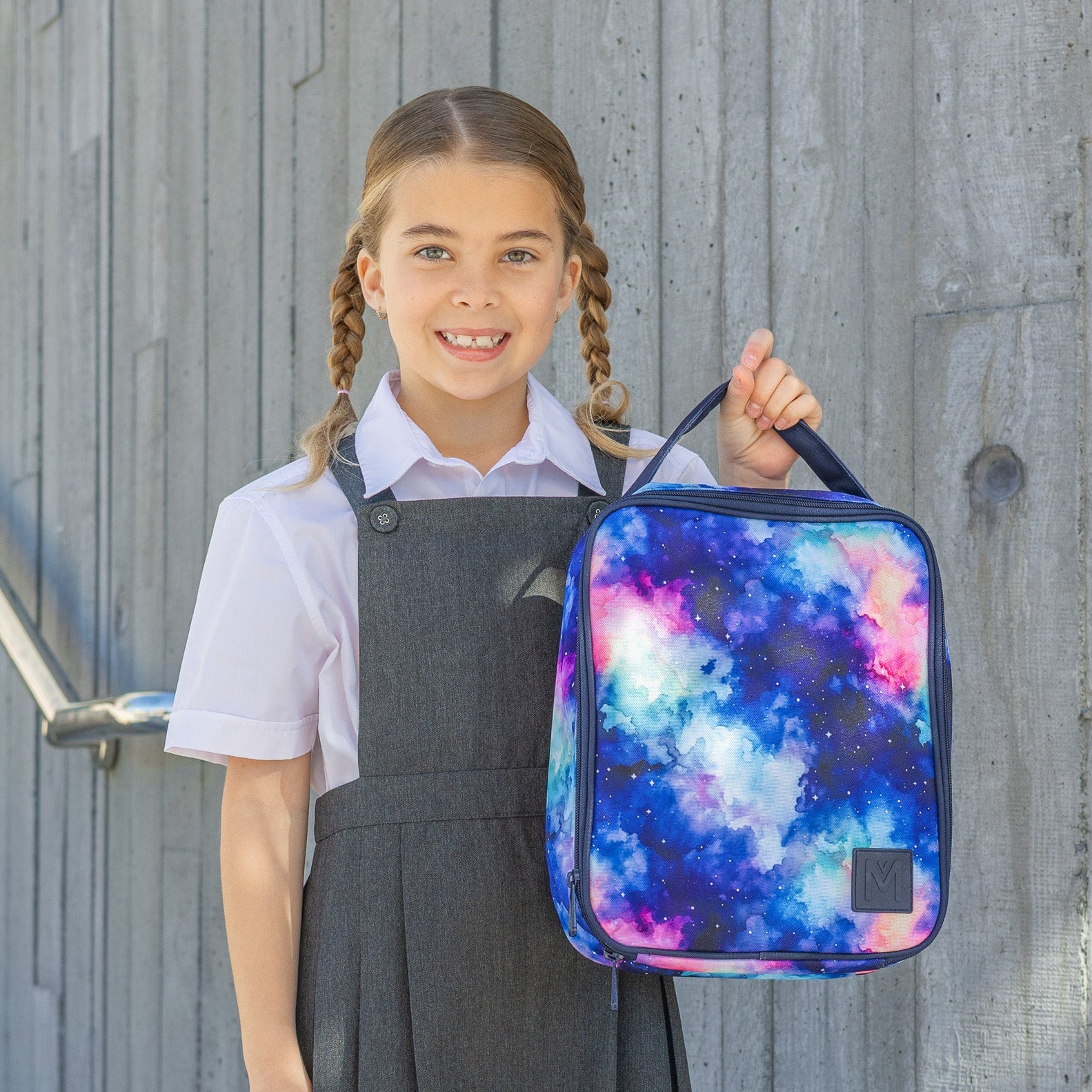 Girl holding a colorful backpack against a wooden background