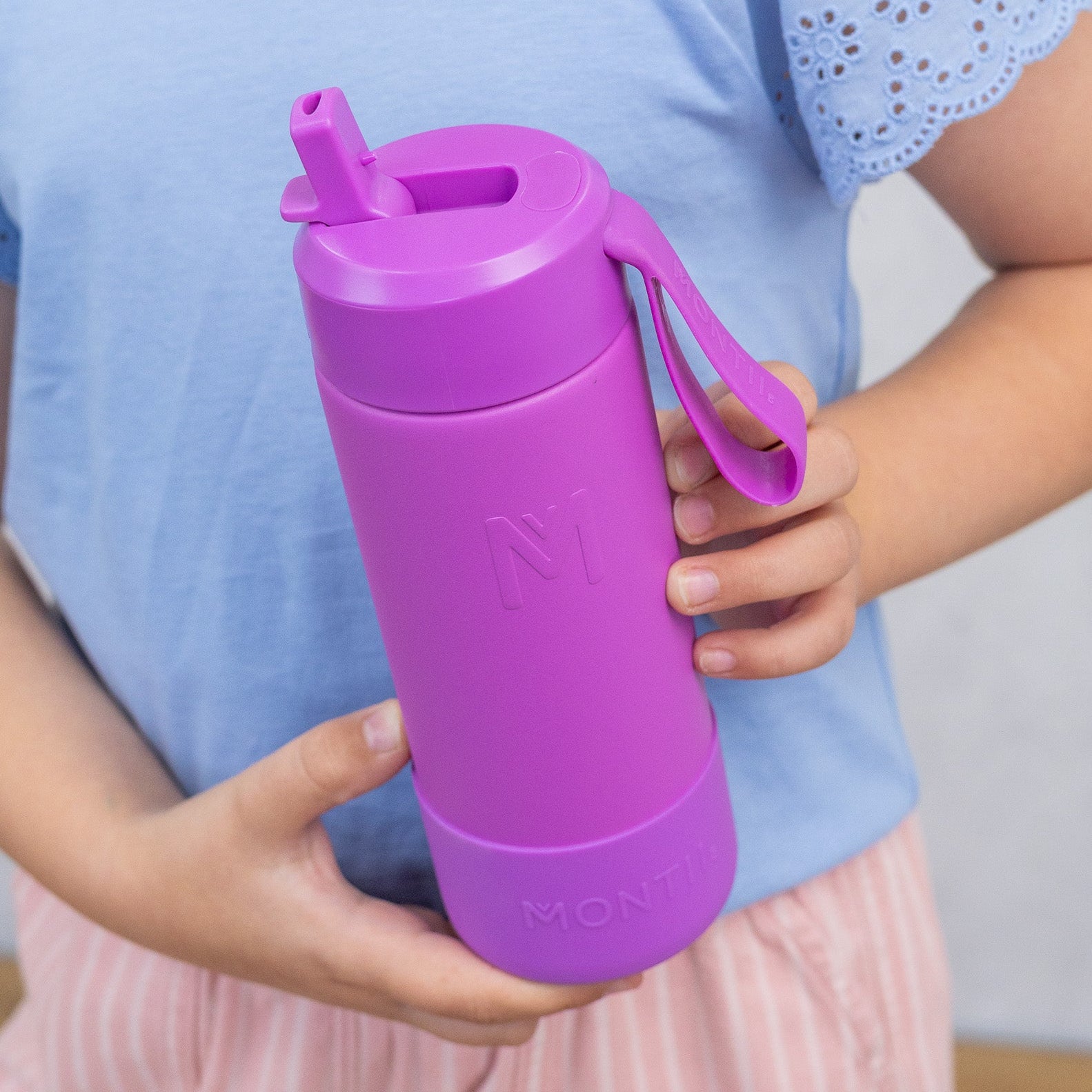 Person holding a purple water bottle with a straw and handle