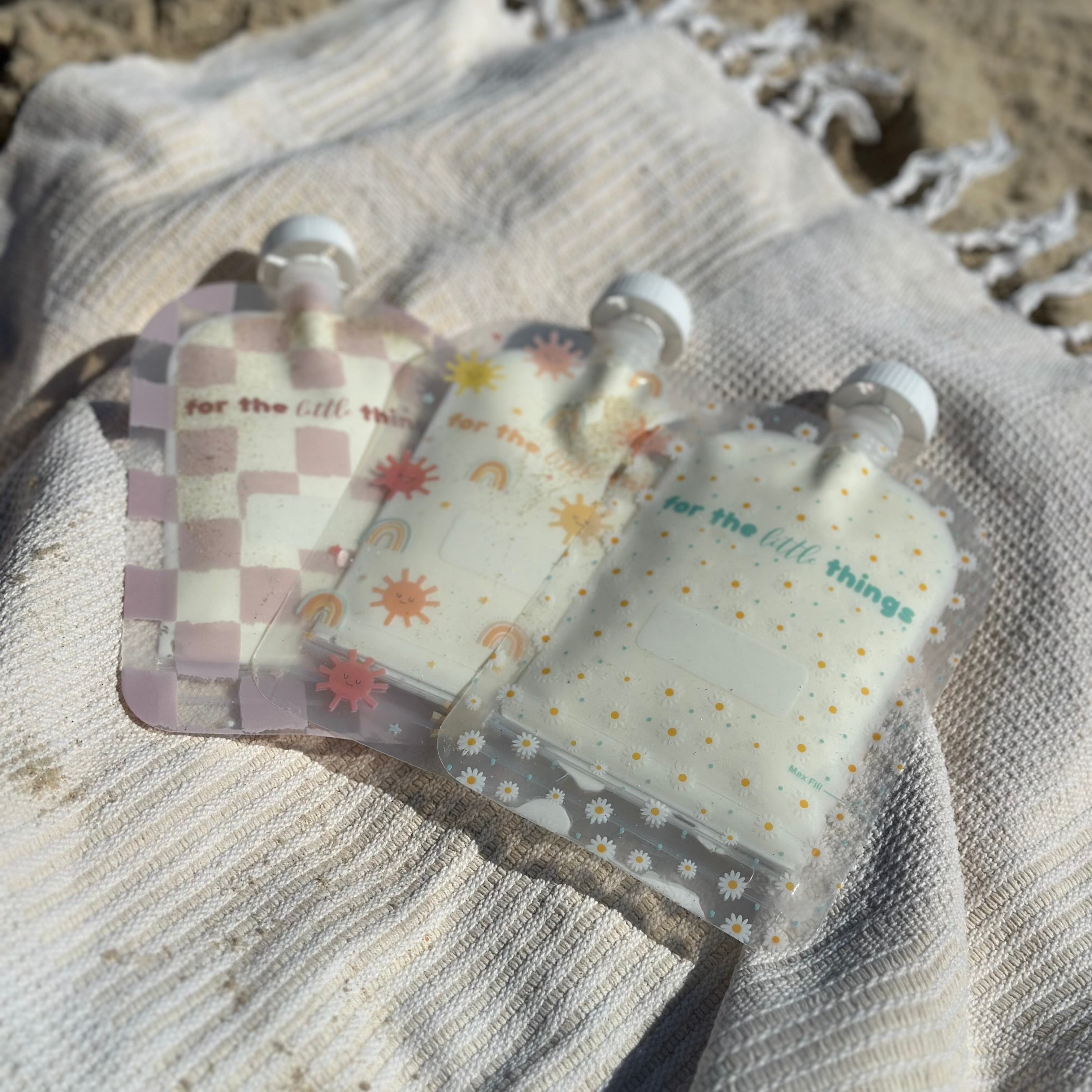 Three decorative keychains on a textured fabric surface with sand in the background